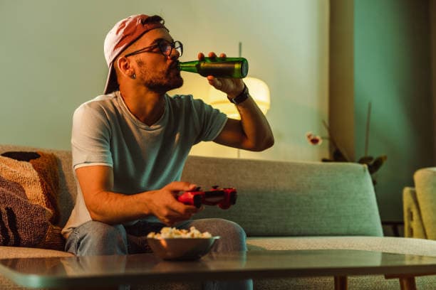 young-man-sitting-on-the-sofa-drinking-beer-and-playing-video-games